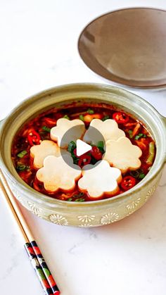 a bowl filled with soup next to chopsticks and a spoon on a table