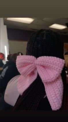 a close up of a person with a pink bow on her head and braids