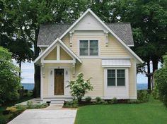 a small yellow house sitting in the middle of a lush green yard