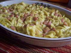 a casserole dish with ham and cheese in it on a red table cloth