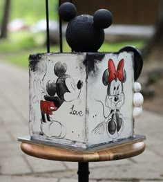 mickey and minnie mouse toasters sitting on top of a wooden stand in front of a brick walkway