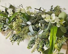 an arrangement of flowers and greenery on a wall