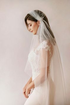 a woman wearing a veil and wedding dress is posing for the camera with her hands on her hips