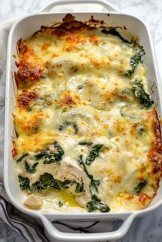 a casserole dish with spinach and cheese in it on a marble table