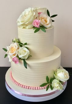 a three tiered cake with white and pink flowers