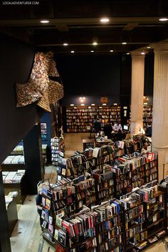 a room filled with lots of books on top of wooden flooring next to tall pillars