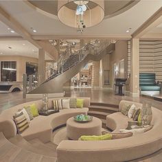 a living room filled with lots of furniture and a spiral staircase leading up to the second floor