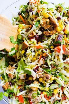 a salad with chicken, beans, corn and lettuce in a glass bowl