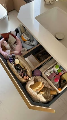 an open drawer in a bathroom filled with cosmetics and other personal care items next to a sink