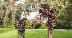 an outdoor wedding ceremony setup with flowers and draping on the altar, surrounded by lush greenery