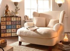 a living room with a white chair and candles on the table in front of it