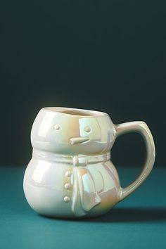 a white ceramic cup with handles on a green surface