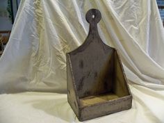 an old metal box sitting on top of a white cloth covered tablecloth in front of a window