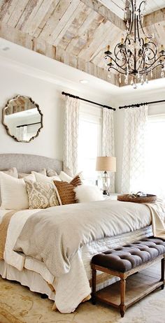 a bedroom with a large bed and a chandelier hanging from it's ceiling