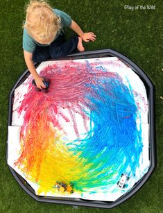 a young child is painting on the ground with colored paint and watercolors in it