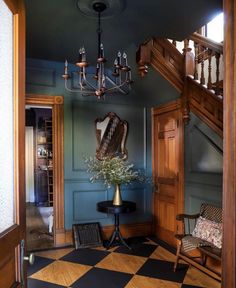 a room with a checkered floor, chandelier and table in it's center