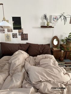 an unmade bed with brown sheets and pillows