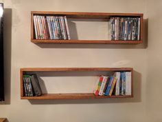 two wooden shelves filled with dvd's next to a wall mounted flat screen tv