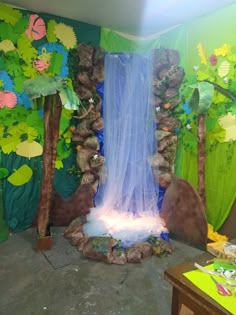 a room decorated with trees, rocks and a waterfall