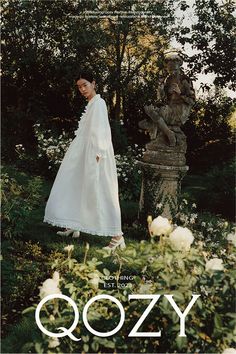 a woman in a white dress standing next to a statue