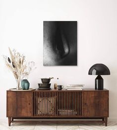 a living room with a wooden entertainment center and artwork on the wall above it,