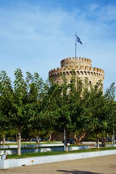 an old brick tower with trees in the foreground and a flag flying on top