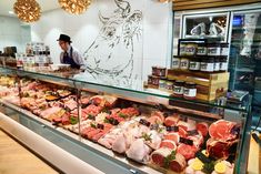 a butcher shop filled with lots of meats and veggies in glass cases