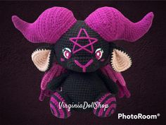 a small stuffed animal with horns on it's head and purple hair is posed in front of a black background