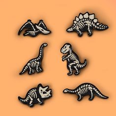 six dinosaur pins in different shapes and sizes on an orange background with the word dino