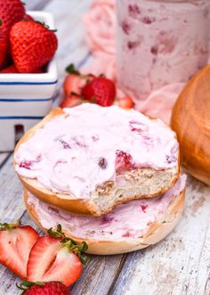 there is a bagel with strawberry cream on it and some strawberries next to it