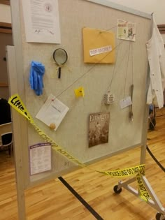 a bulletin board with caution tape on it and various items taped to the wall behind it