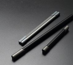 two black pens sitting on top of a table next to each other