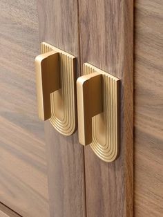 two brass handles on wooden cabinets with wood grained doors and drawers in the background