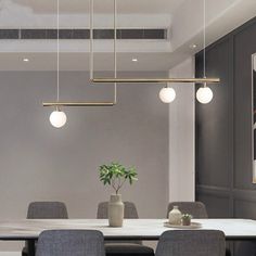 a dining room table and chairs with lights hanging from the ceiling