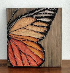 an orange and black butterfly painted on wood