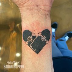 a heart shaped tattoo with two skateboarders on it's wrist and the word love written in black ink