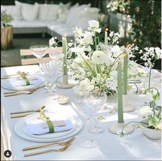 the table is set with white flowers and gold place settings for an elegant dinner party