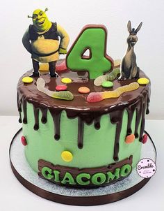 a green birthday cake with chocolate frosting and cartoon characters on top, including the number four