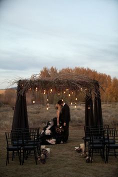 a couple kissing in front of an outdoor ceremony