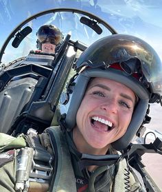 a woman is smiling while sitting in the cockpit of an airplane with another person behind her