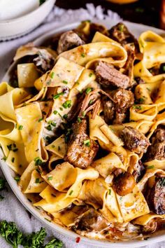 a plate full of pasta with meat and parmesan cheese on the side next to an orange