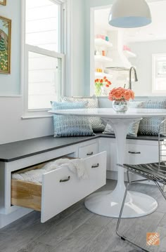 a kitchen with white cabinets and gray counter tops, an island table in the center