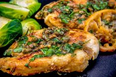 chicken with herbs and sliced vegetables on a black plate, ready to be cooked in the oven