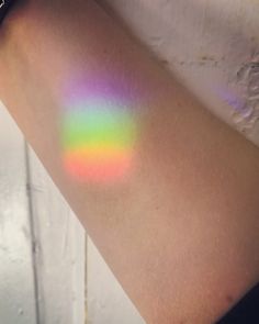 a person's arm with a multicolored stain on it and the sun shining through