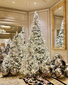 a white christmas tree sitting on top of a table next to silver balls and mirrors