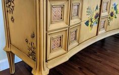 an old dresser with painted flowers on the doors and drawer fronts is shown in this image