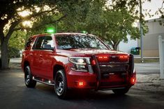 a red truck parked in front of a tree with green lights on it's roof