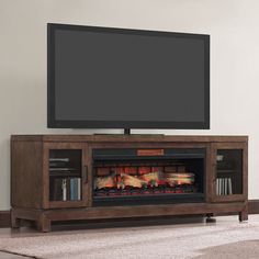 a flat screen tv sitting on top of a wooden entertainment center next to a fireplace