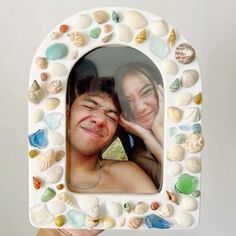 a man and woman are smiling in a frame made out of seashells