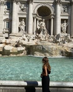 a woman standing in front of a water fountain